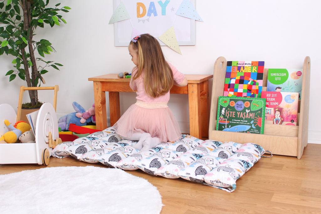 a little girl in a pink dress sitting on a bed